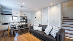 Una cocina moderna con zona de comedor, un sofá con cojines estampados y una escalera.