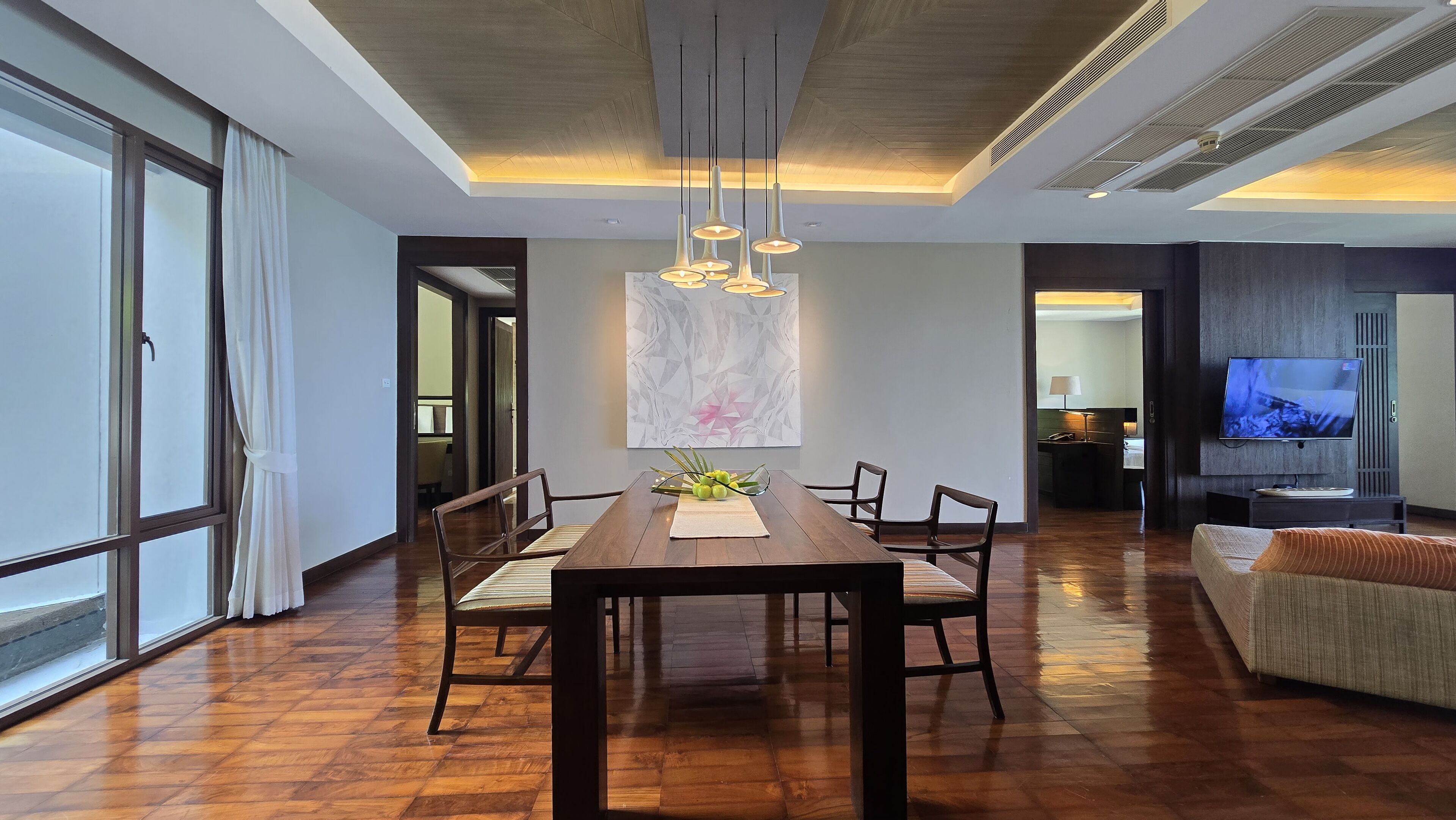 A modern dining area with a wooden table, chairs, and a centerpiece of green apples.