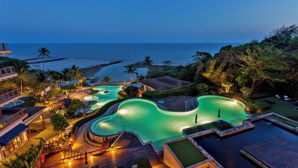 A resort with multiple swimming pools, a beach view, and a well-lit deck area. - Luaana@CasaVela - 2BR Apartment with Ocean View (Koh Samui)