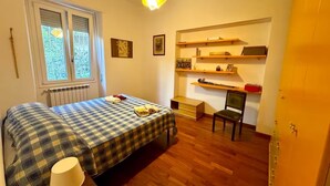 Una habitación con una cama, una silla, un escritorio y estanterías con diversos objetos.