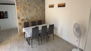 Un comedor con una mesa, sillas, un muro de piedra y un ventilador.