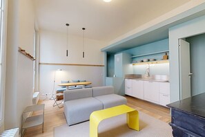 Una sala de estar moderna con sofá, una mesa de centro, un comedor con mesa y sillas, y una cocina con armarios y encimera.