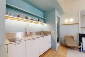 Una cocina moderna con armarios blancos, encimera de acero inoxidable y una pared de acento azul.