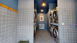 Une buanderie équipée de deux machines à laver, d’un radiateur et d’un tableau encadré accroché au mur.
