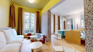 Un salon moderne comprenant un canapé, des fauteuils, une table basse et un petit coin repas.