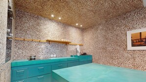 A kitchen with a speckled backsplash, teal cabinetry, and a wooden shelf above the counter. - JOIVY Pleasant 1-bed flat w/ shared courtyard (Paris)