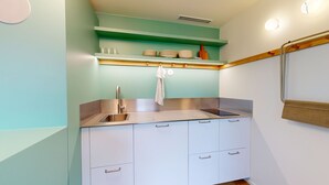 A compact kitchen with a stainless steel sink, white cabinets, and a green wall. - JOIVY 10 Douai 1BR Velux (Paris)