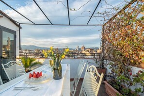 Una terraza con una mesa preparada para dos personas, una botella de vino y un plato de fresas.