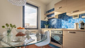 Una cocina moderna con una mesa de comedor de vidrio, azulejos azules y un amplio ventanal.