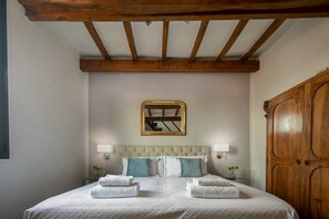 Ein Schlafzimmer mit einem großen Bett, Holzbalkendecke, einem Spiegel und einem Kleiderschrank.