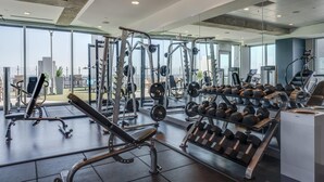 A modern gym with various weightlifting equipment, cardio machines, and dumbbells.