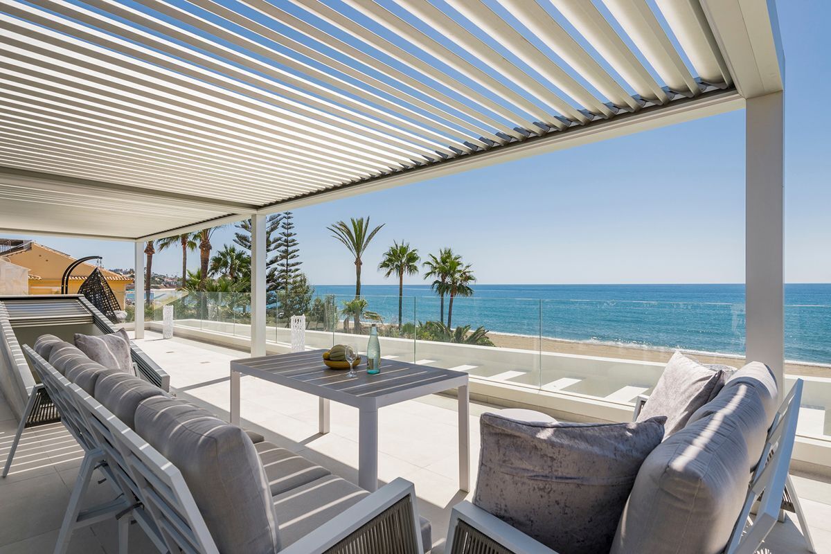 A covered outdoor seating area with a view of the beach and ocean.