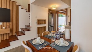 A dining area with a wooden table set for four, a TV mounted on the wall, and a staircase with wooden steps. - House w/ Pool 900m From the Beach, Arraial Ptg0030 (Porto Seguro)