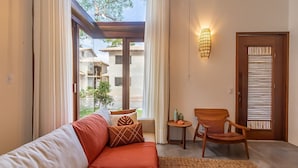 A modern living room with a sofa, chairs, a small table, and a view of a building through large windows. - House w/ Pool 900m From the Beach, Arraial Ptg0030 (Porto Seguro)