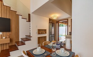 A dining area with a wooden table set for four, a TV mounted on the wall, and a staircase with wooden steps. - House w/ Pool 900m From the Beach, Arraial Ptg0030 (Porto Seguro)