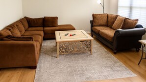 Una sala de estar con un sofá marrón, un sillón negro y una mesa de centro de madera.