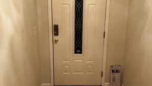 Una puerta blanca con un panel de vidrio decorativo y una pequeña caja en el suelo a su lado.