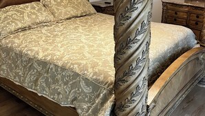 Una cama con dosel con un cabecero y piecero de madera tallada, un dosel a juego y una colcha con estampado floral.