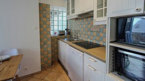 A compact kitchen with white cabinets, a built-in oven, and a window with a view. - "La maison du bonheur" (Bois-le-Roi)