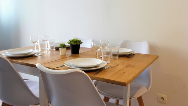 A dining table set with plates, glasses, and cutlery, surrounded by white chairs. - "La maison du bonheur" (Bois-le-Roi)