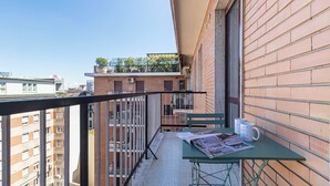 Un balcon avec une table, deux tasses blanches et des journaux.
