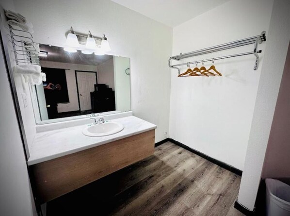 Un baño con lavamanos blanco, espejo y suelo de madera.