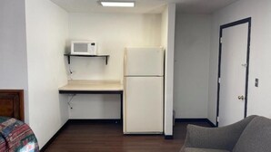 A compact room with a kitchenette, a bed, and a door. - Hotel O (Oskaloosa)