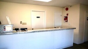 A reception desk with a white counter and a door labeled "Reception". - Hotel O (Oskaloosa)