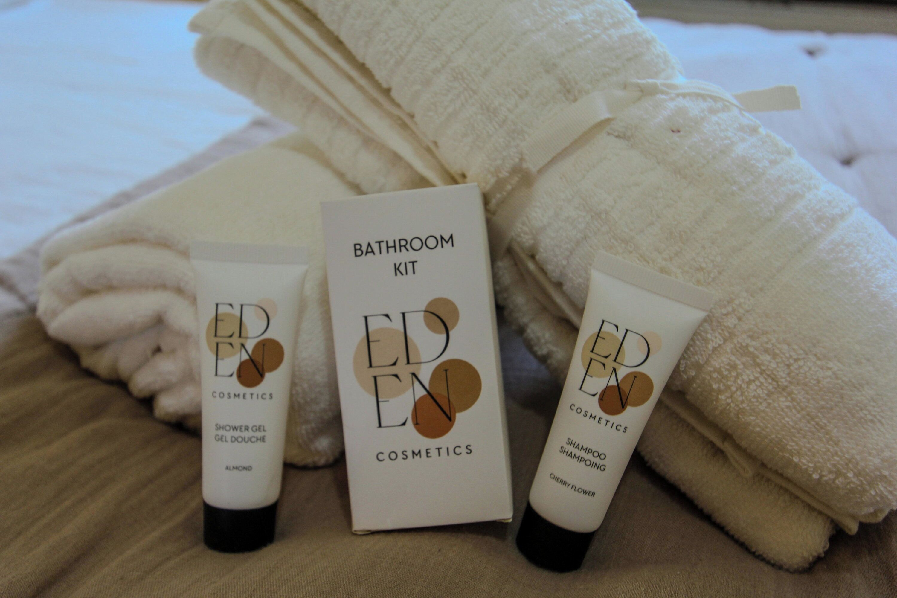 A bathroom kit with a shower gel, shampoo, and a box labeled 'EDEN COSMETICS.'