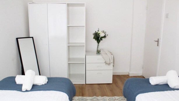 Un dormitorio con dos camas, un armario, un tocador y un espejo.