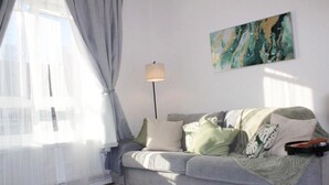 Una sala de estar con un sofá gris, una lámpara de pie y un cuadro en la pared.