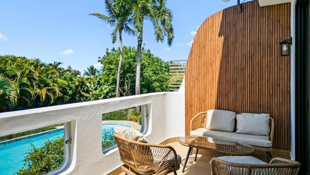 A balcony with a pool, wicker furniture, and a wooden wall.