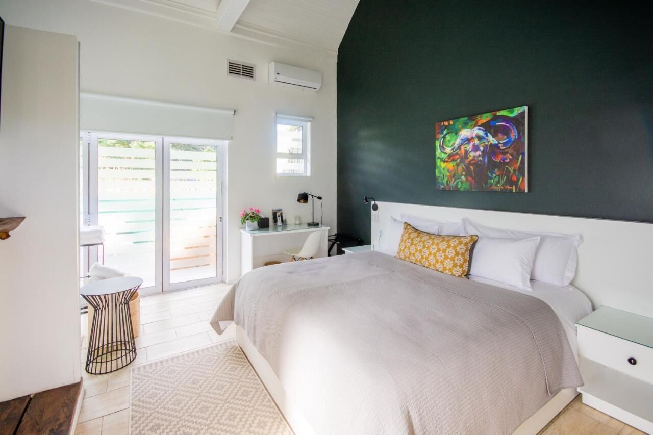 A bedroom with a large bed, a desk, a chair, and a window.