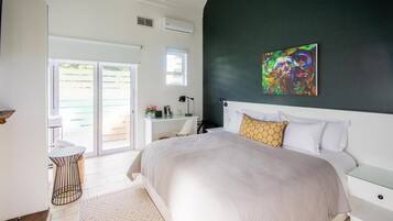 A bedroom with a large bed, a desk, a chair, and a window.