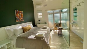 Une chambre moderne avec un grand lit, une porte vitrée donnant sur un balcon et une vue sur l’extérieur.