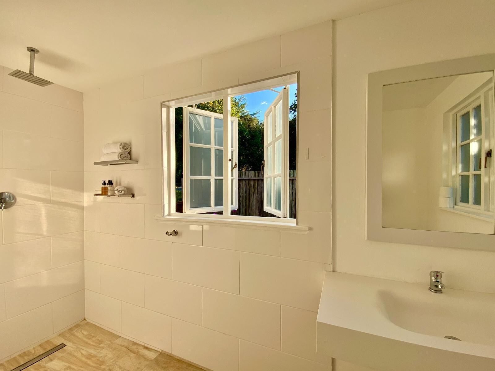 A bathroom with a window, a shower, and a sink.