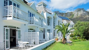 Une maison blanche à deux étages, dotée d’un balcon, de panneaux solaires et offrant une vue sur les montagnes.