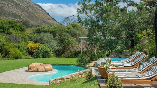 Un espace piscine avec des chaises longues et une vue sur les montagnes en arrière-plan.