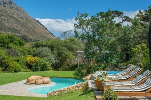 Poolbereich mit Liegestühlen und Bergblick.