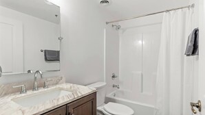 A bathroom with a sink, mirror, toilet, and bathtub. - Amazing Riverfront Views - Steps from Arch (St. Louis)