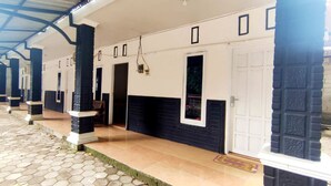 A covered walkway with hexagonal tiles, white walls with black accents, and doors with windows. - Backpacker Homestay (Sumberagung)