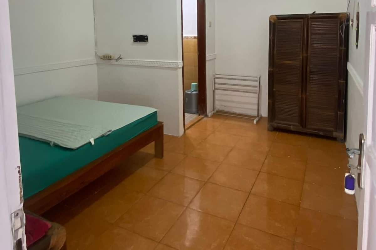 A room with a bed, a radiator, a wardrobe, and a ceiling fan.