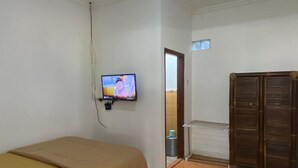 A room with a bed, a television, a wardrobe, and a tiled floor. - Backpacker Homestay (Sumberagung)