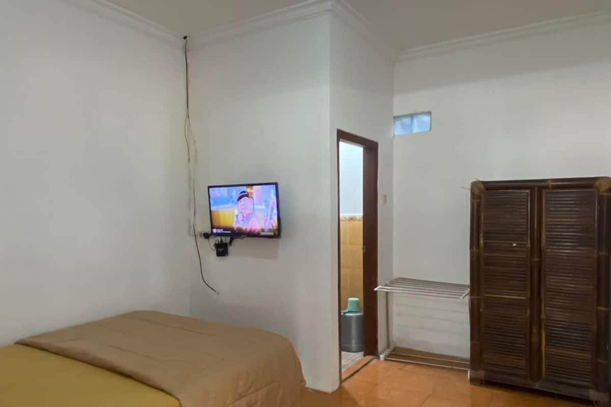 A room with a bed, a television, a wardrobe, and a tiled floor.