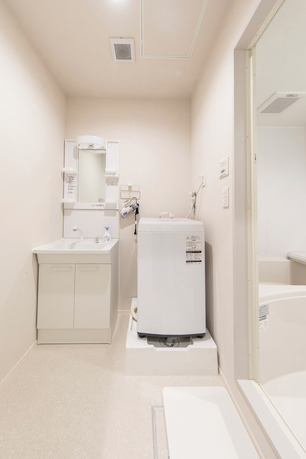 Un baño pequeño con lavamanos, espejo y un armario blanco.