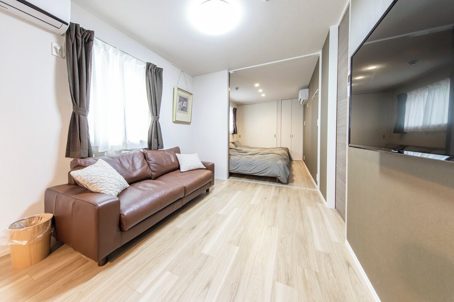 Una sala de estar moderna con un sofá de cuero, una cama y una cocina integrada.