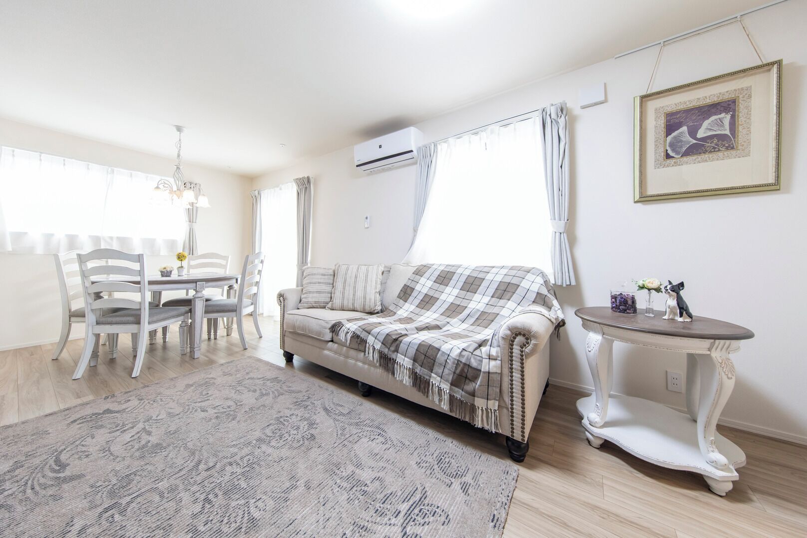 A living room with a sofa, dining table, chairs, and a small table with a decorative item.