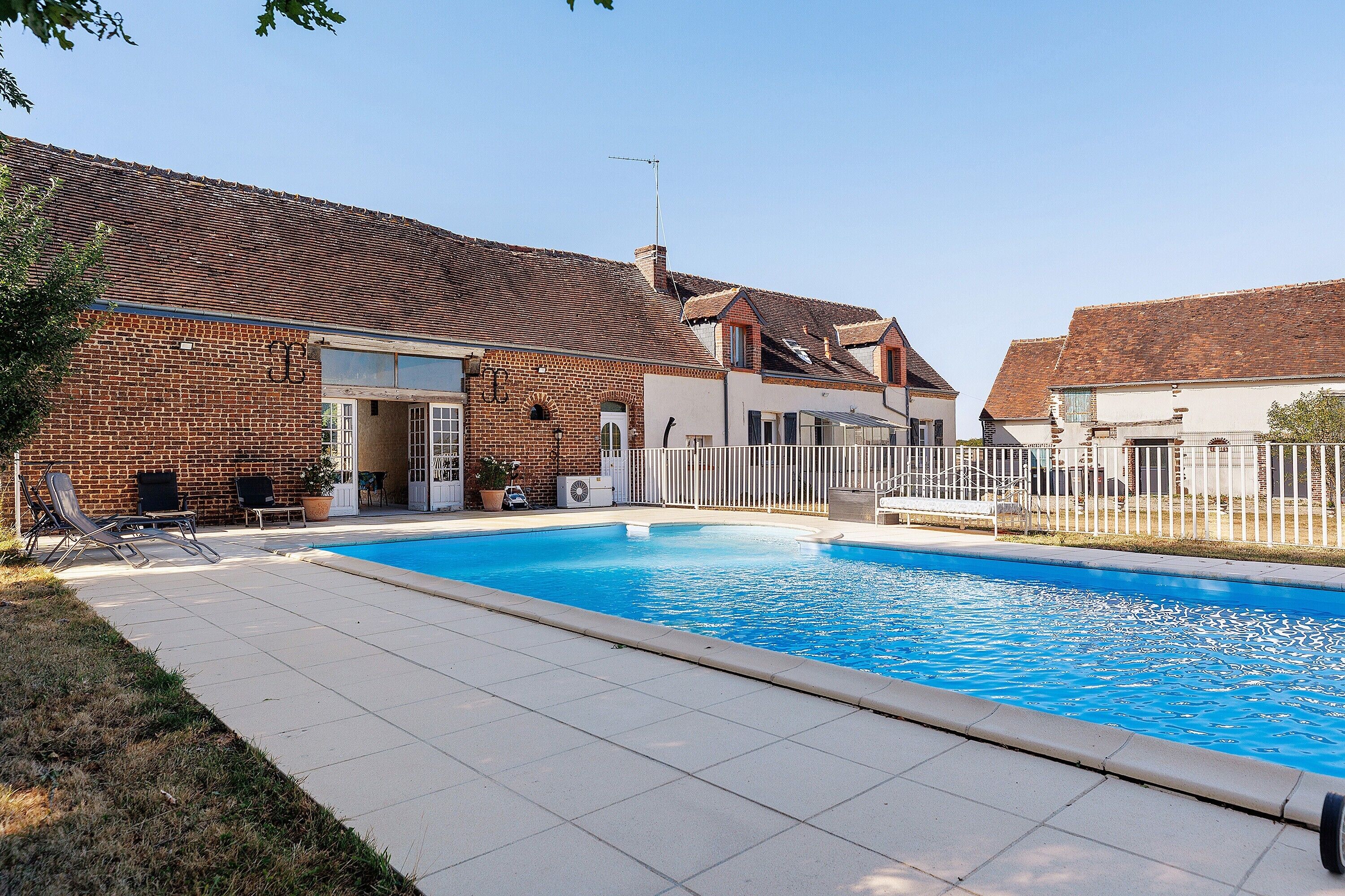 A swimming pool with a brick house in the background.