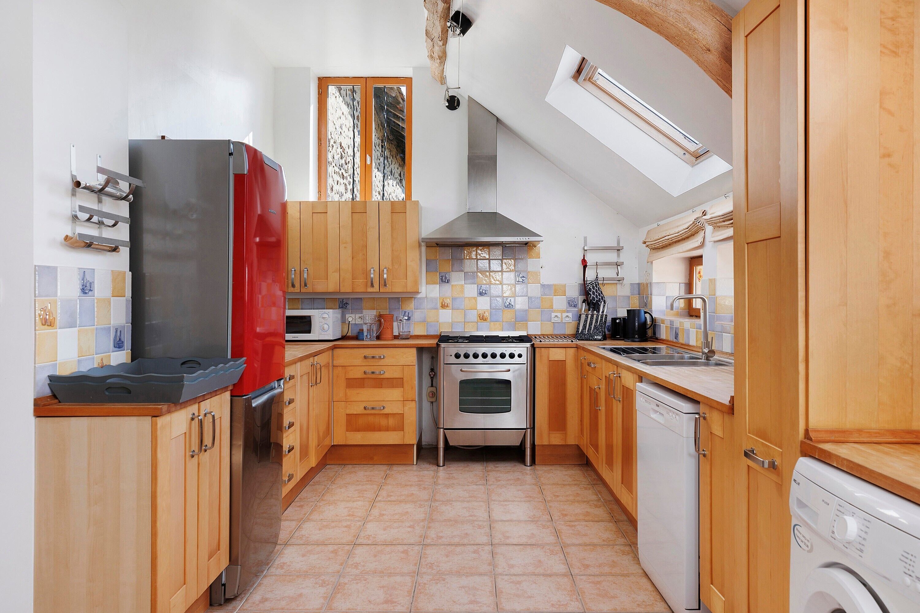 A kitchen with wooden cabinets, a stainless steel refrigerator, an oven, a dishwasher, and a washing machine.