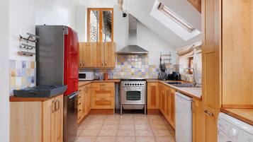 A kitchen with wooden cabinets, a stainless steel refrigerator, an oven, a dishwasher, and a washing machine.
